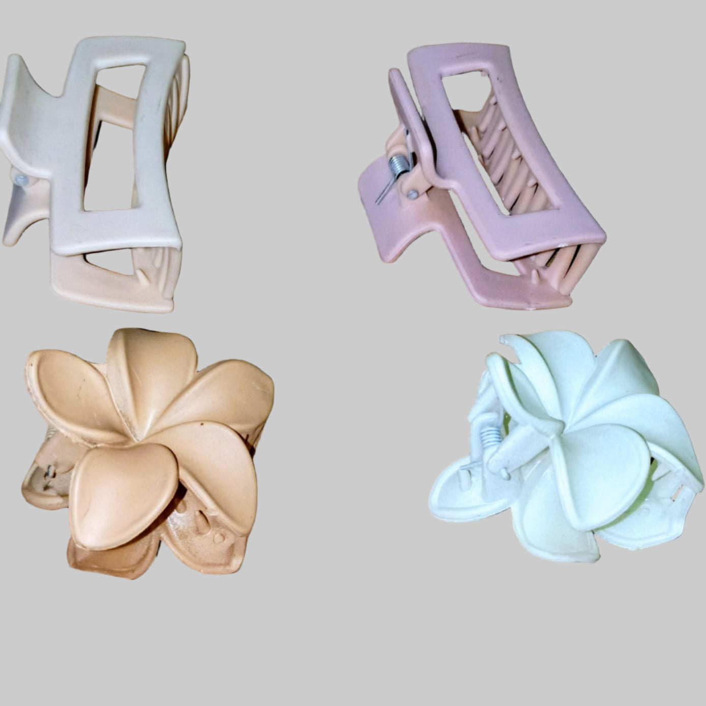 Four hair clips in different designs on a wooden surface